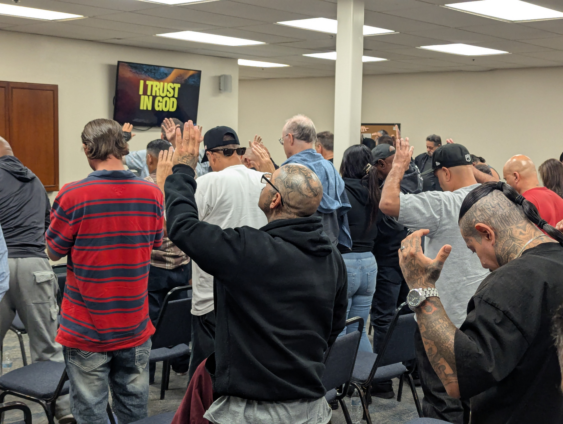 Community members raising hands in prayer at a Good Samaritan ReEntry gathering